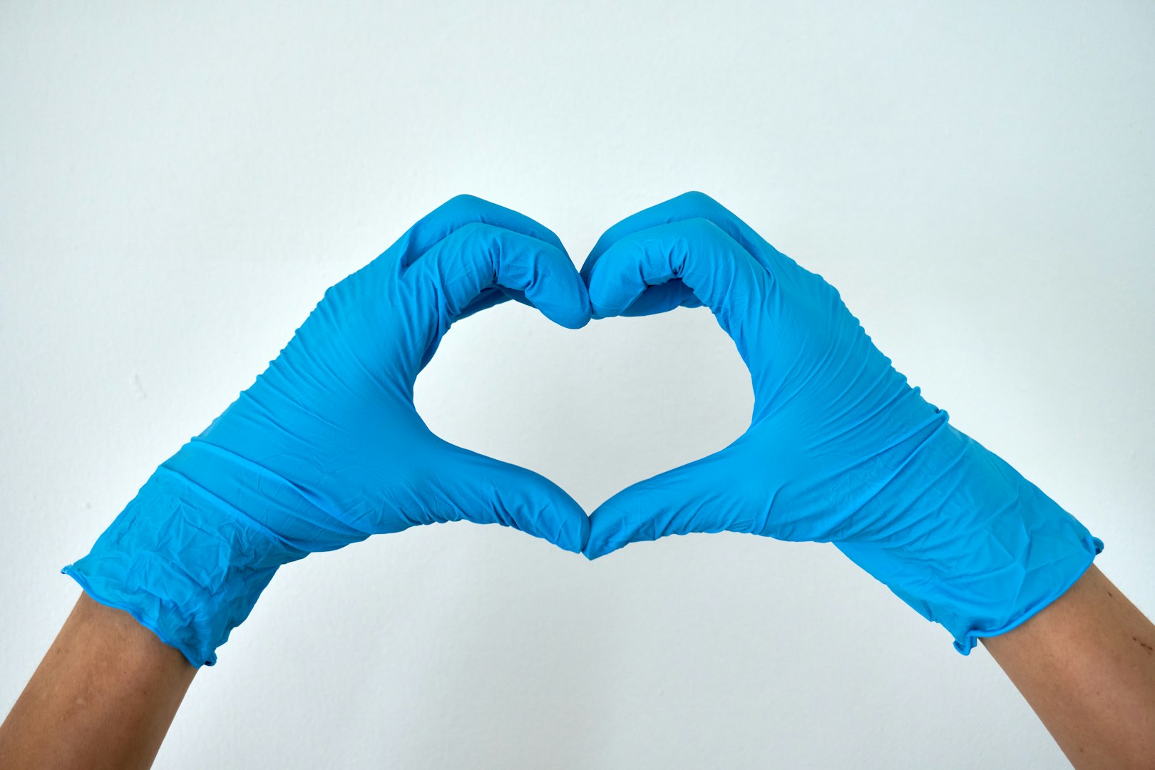 blue gloved hands making heart sign